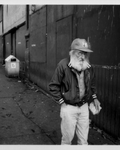 Elderly homeless man walking on sidewalk